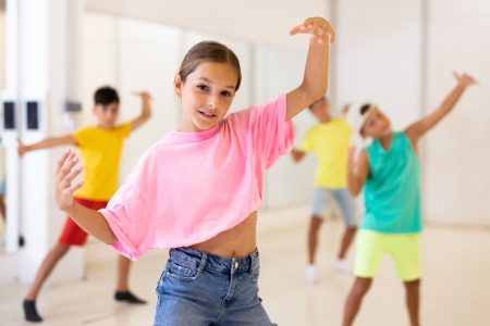 Girl and her mates training modern dance moves together in studio.