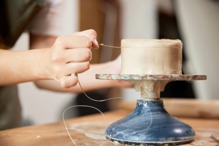 Closeup hands of female ceramis artist working at pottery studio on pottery wheel. Handcrafted products. Creative people, hobbies and skills. Concept of art, fashion, self-development and ad